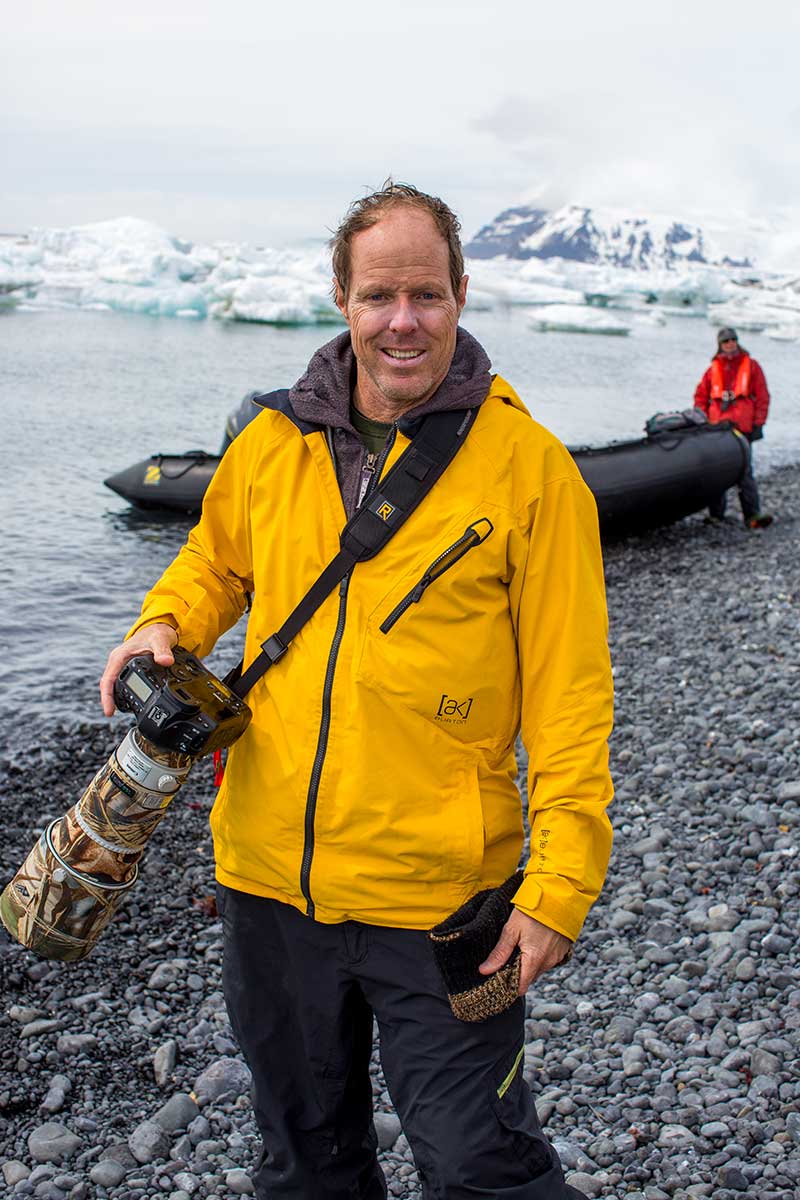 Nature photographer Mark Coulbourne amidst a sea of penguins in Antarctica, ready to capture the beauty of the frozen landscape. Explore and buy wall prints from this extraordinary expedition.